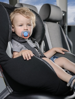 Kleiner Junge mit Schnuller sitzt im Kindersitz Test im Auto